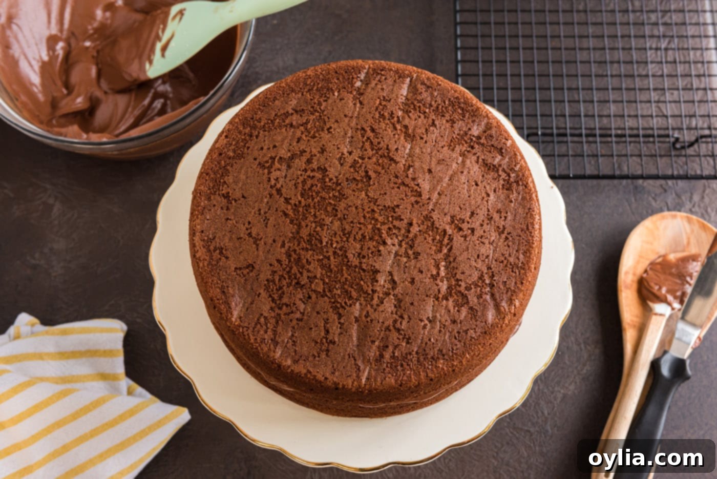 Two round chocolate cake layers are carefully placed on top of each other, forming the base of a two-tiered cake with a layer of frosting in between.