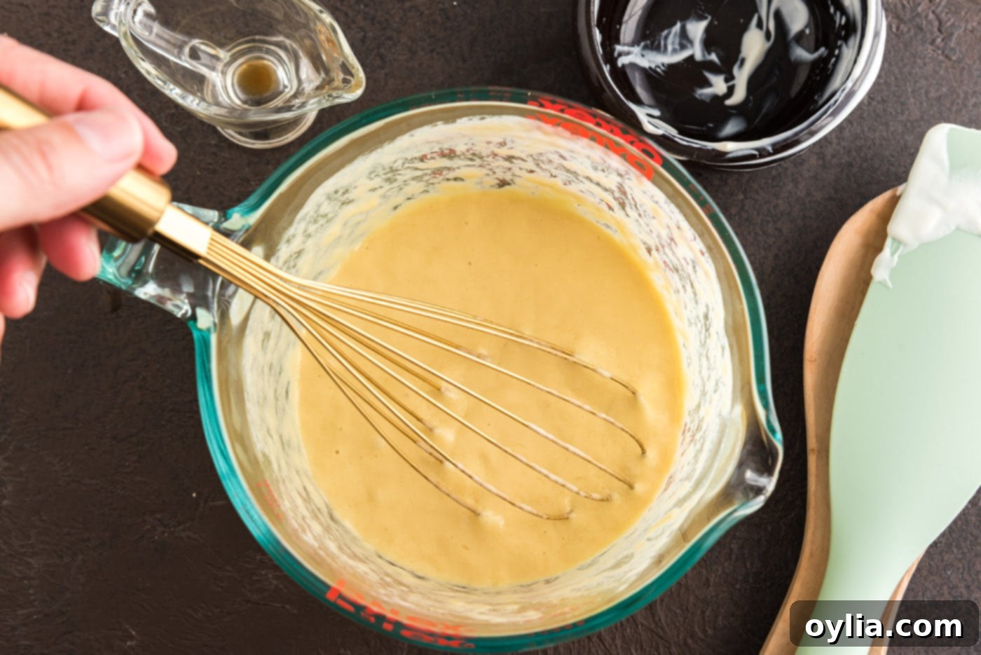 The wet ingredients, including eggs, sour cream, and vanilla, are fully whisked in a bowl, showing a smooth, pale yellow mixture.