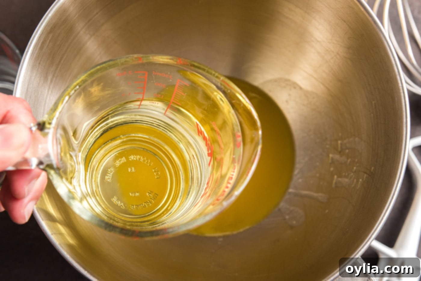 Canola oil being poured into a bowl containing melted butter, preparing for the next step in the chocolate cake batter.