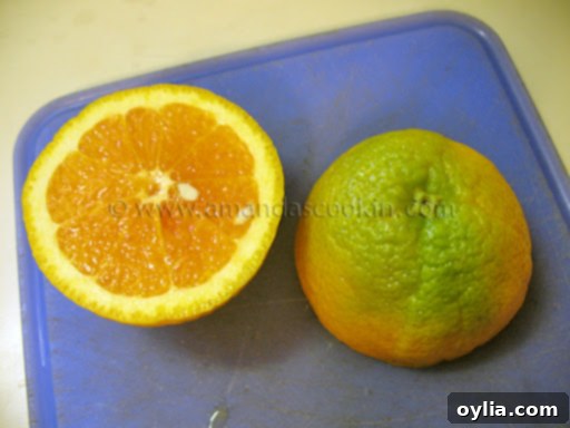 Close-up of a Sunkist Valencia orange sliced in half, revealing bright orange, ripe flesh despite a partially green peel