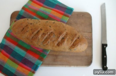 A loaf of scallion chive bread with garlic and rosemary on a wooden cutting board.