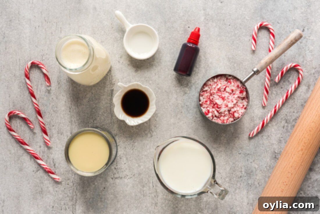 A flat lay photograph showing all ingredients laid out for making Homemade Peppermint Ice Cream: sweetened condensed milk, heavy cream, milk, peppermint extract, vanilla extract, red food coloring, and crushed peppermint candies.