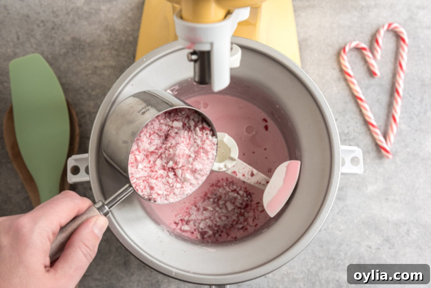Pouring crushed peppermint candies into the ice cream maker towards the end of the churning cycle.