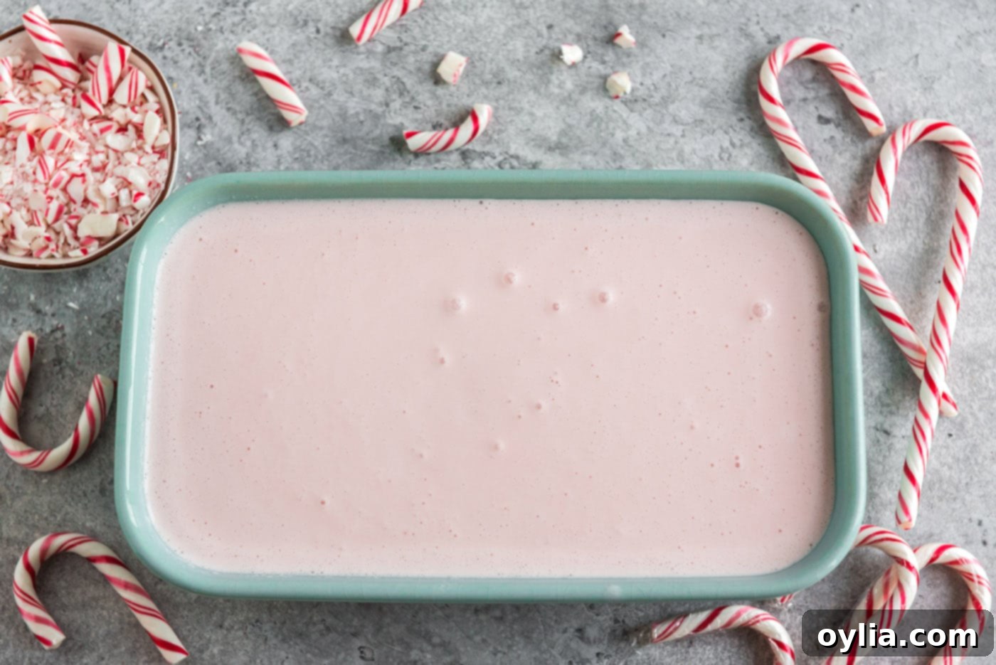 Freshly churned homemade pink peppermint ice cream transferred into a freezer-safe container for final setting.