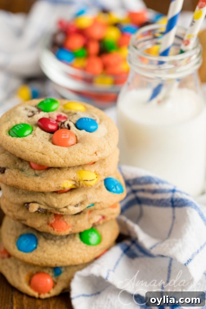 Two jumbo M&M cookies with milk, showcasing their generous size and colorful candies.