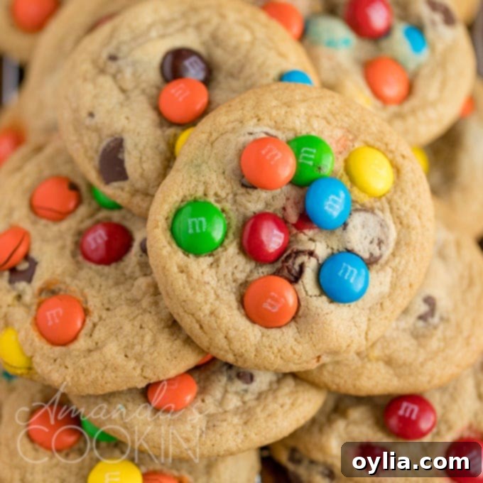 pile of M&M chocolate chip cookies on a white plate