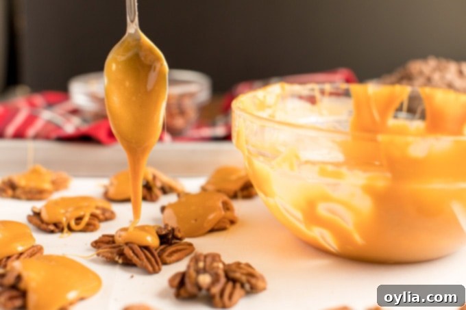 spoon applying melted caramel to a pecan cluster