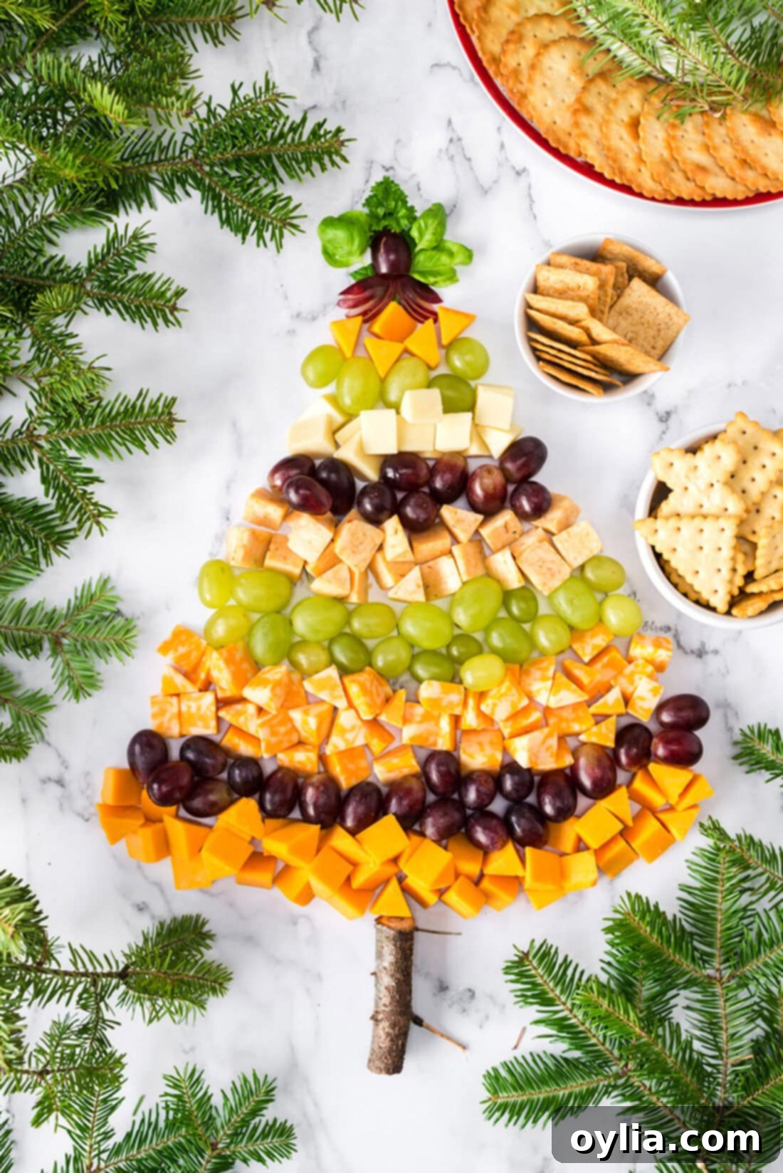 Overhead photo of a festive Christmas Tree Cheese Platter adorned with cheeses and grapes, perfect for holiday parties