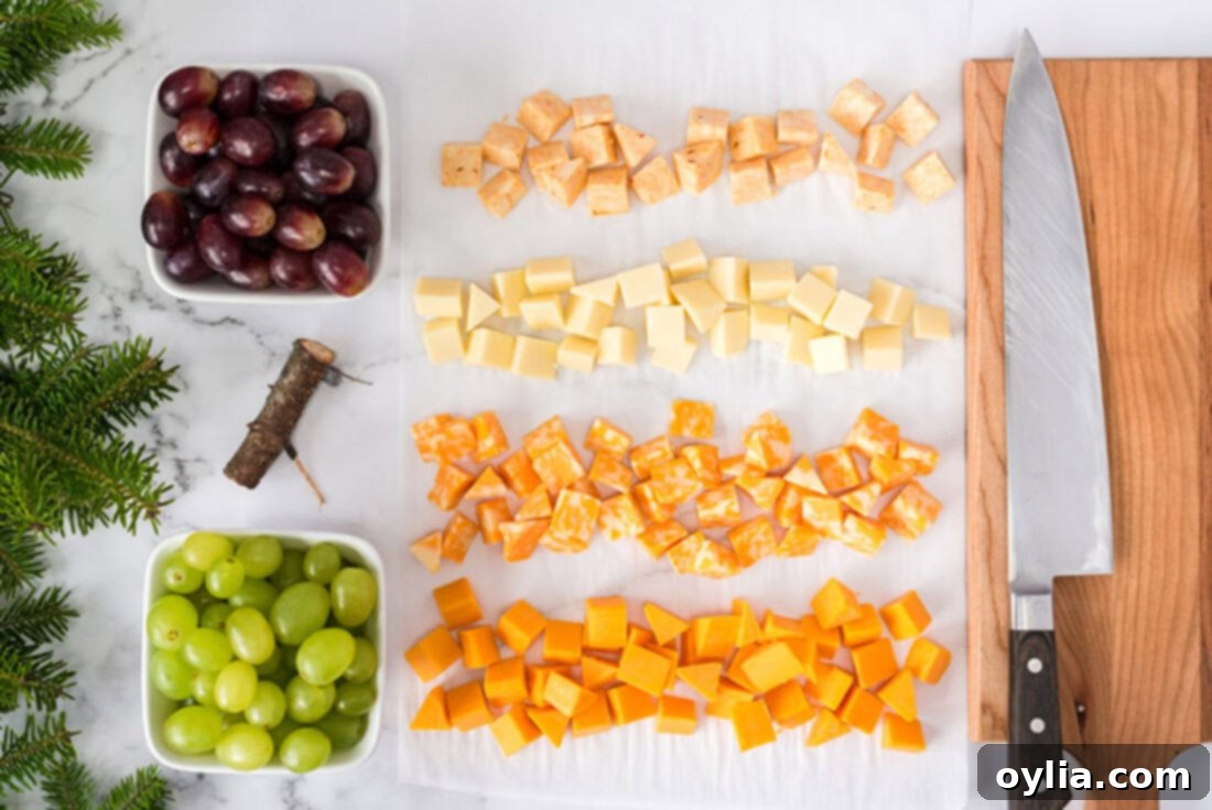Collection of ingredients for Christmas Tree Cheese Platter including various cheeses, red and green grapes, and fresh herbs