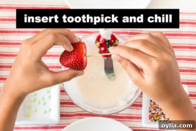 A hand inserting a toothpick into the flat cut end of a fresh strawberry.