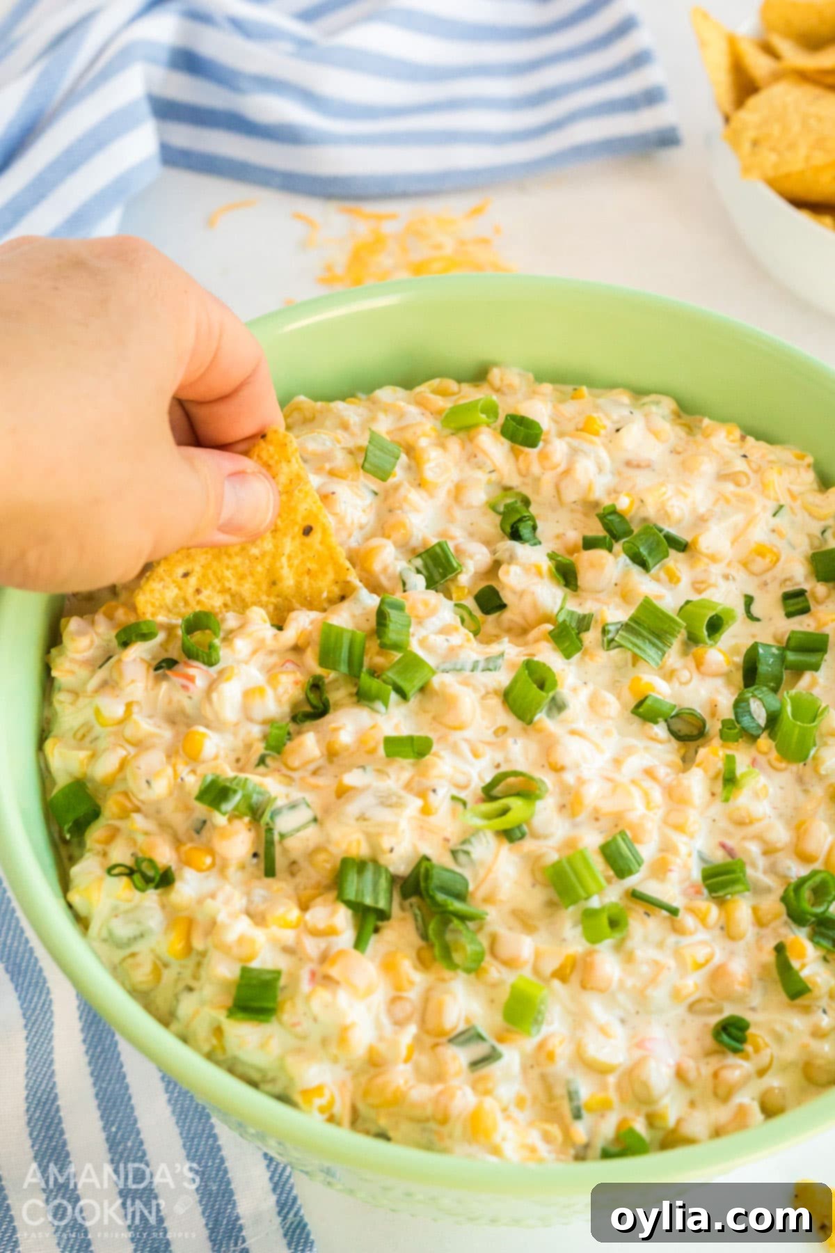 hand scooping corn dip with tortilla chip