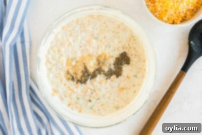 bowl of corn dip with seasonings added to the top of it