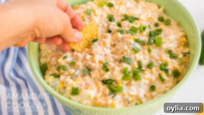 hand dipping tortilla chip in corn dip