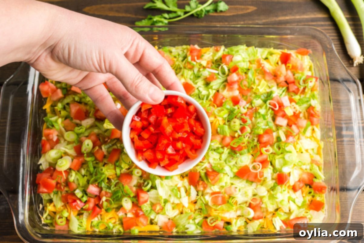 sprinkling toppings over taco dip