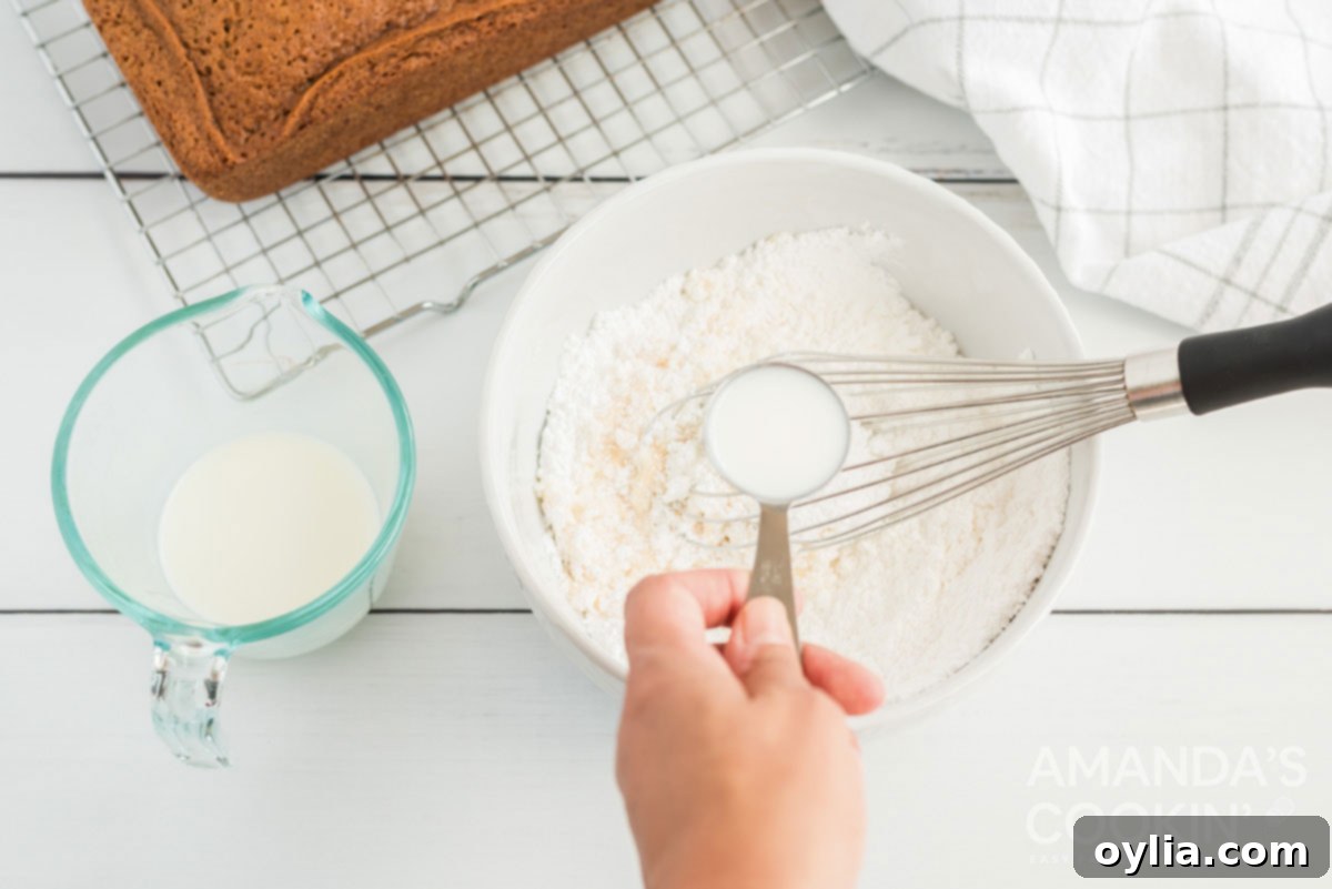 Adding milk to sifted powdered sugar and vanilla to create a smooth glaze.
