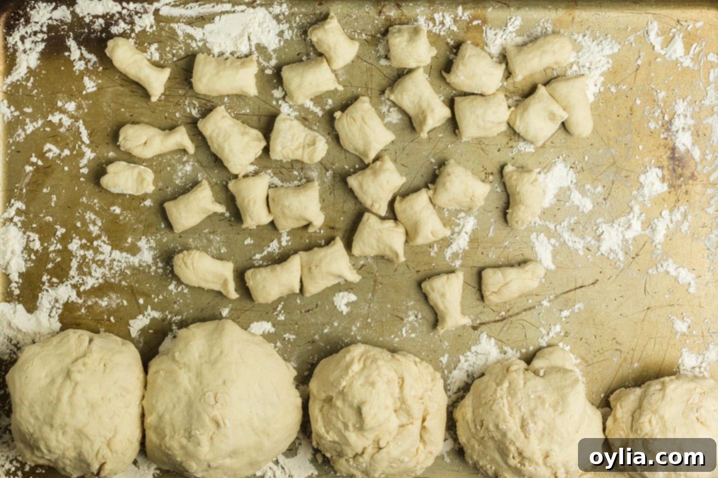 Pretzel dough ropes cut into small, even bite-sized pieces on a floured surface.
