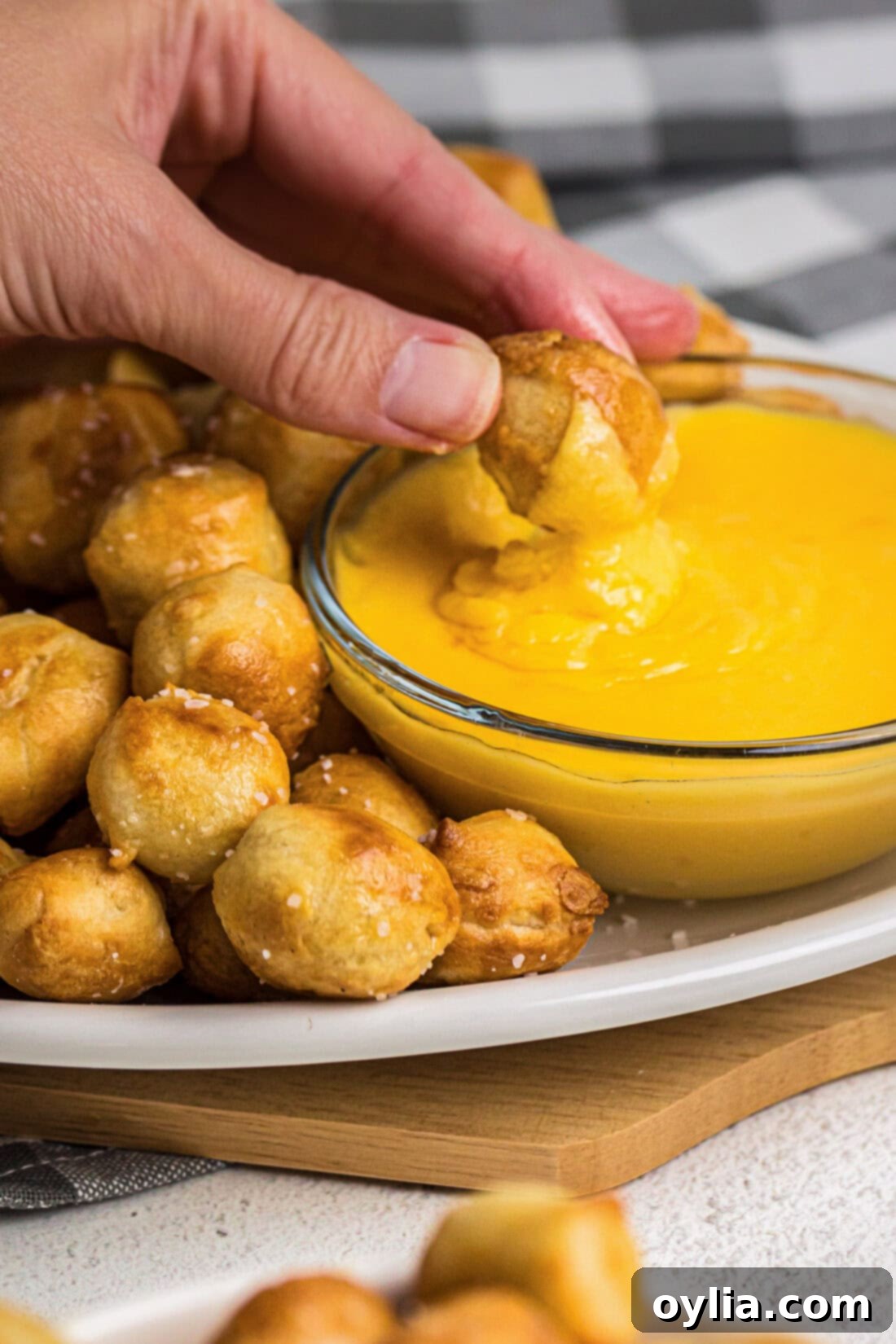 Air Fryer Pretzel Bite being dipped into a luscious cheese sauce, highlighting its golden crust.