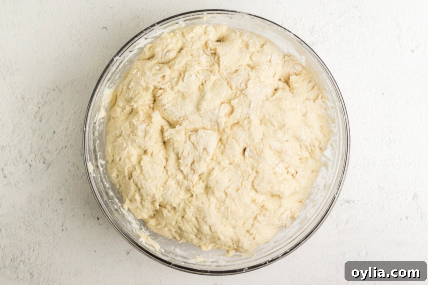 Dough resting in a bowl, covered with a towel, during its rising period.