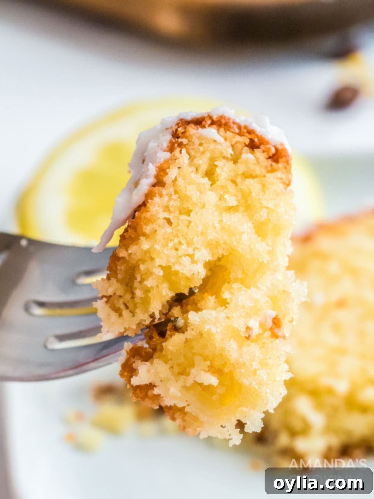 fork holding a piece of copycat starbucks lemon loaf, showing its perfect texture and glaze
