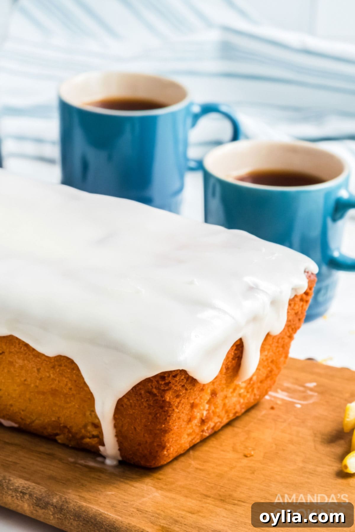 glazed quick bread with coffee cups in background, emphasizing its perfect pairing with a warm beverage