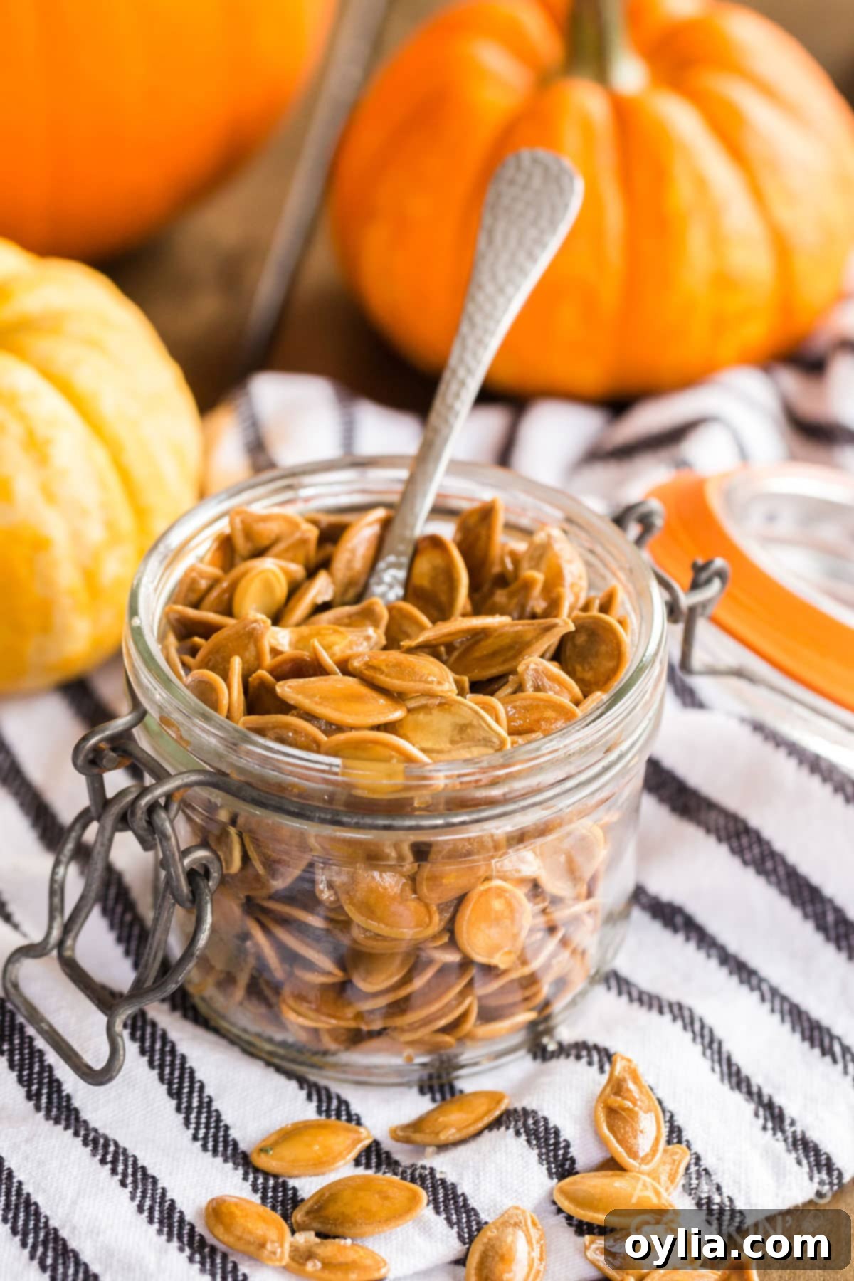 There's something nostalgic about a pan full of salty roasted pumpkin seeds! It's a fall and Halloween tradition after carving pumpkins. small jar of pumpkin seeds with a spoon, symbolizing a delicious fall and Halloween tradition.