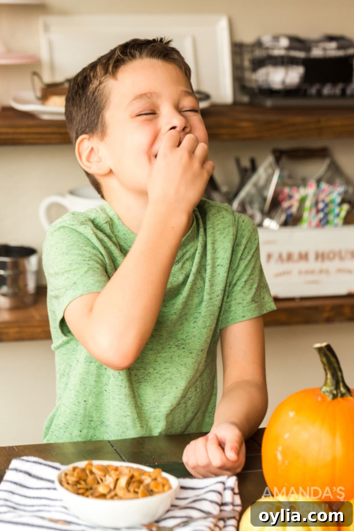 There's something nostalgic about a pan full of salty roasted pumpkin seeds! It's a fall and Halloween tradition after carving pumpkins. child happily eating roasted pumpkin seeds, showcasing them as a family-friendly fall snack.