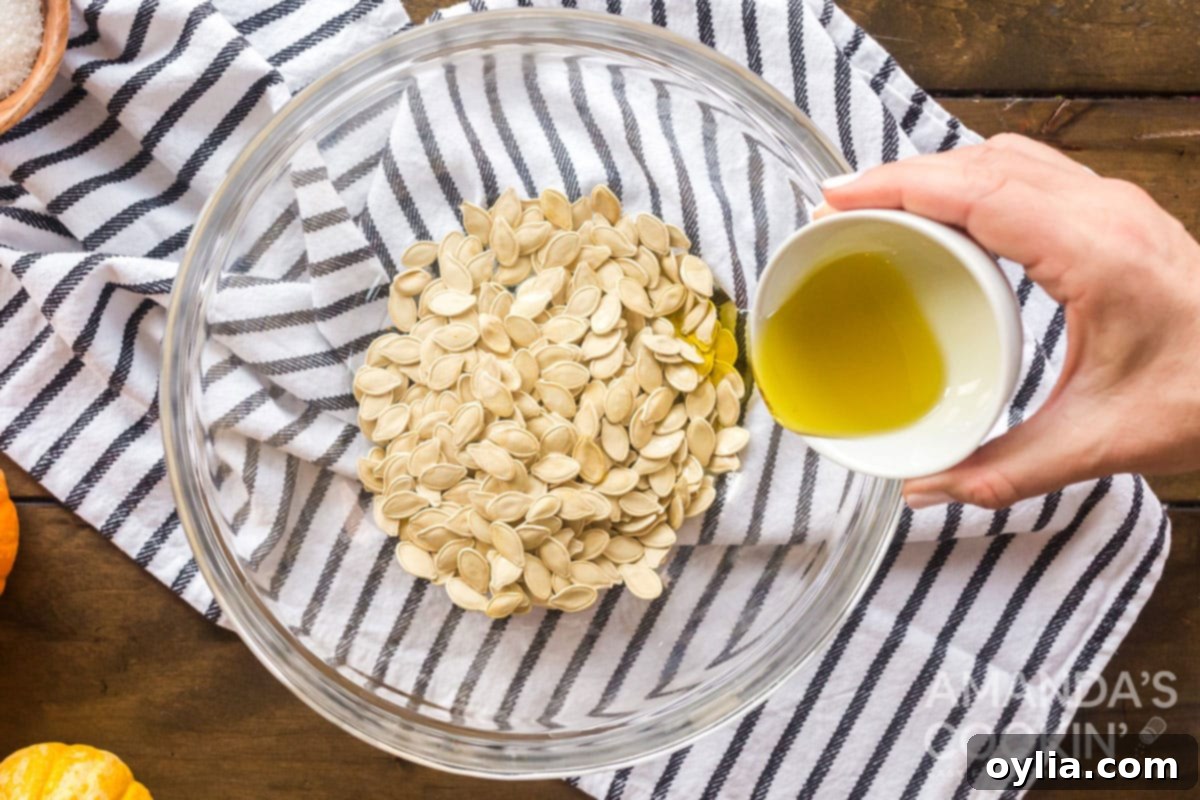 Golden Roasted Pepitas 7 adding olive oil to pumpkin seeds in a bowl, preparing them for roasting.