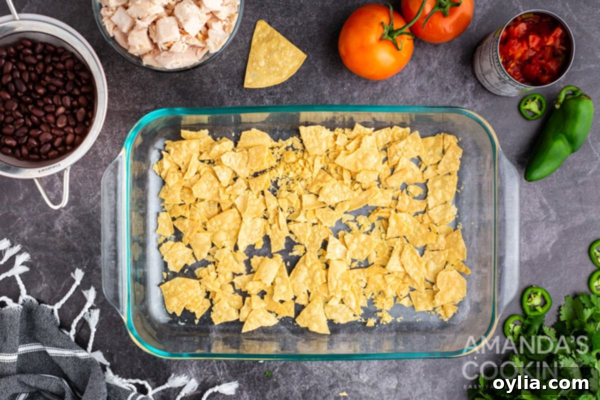 Crushed tortilla chips spread evenly in the bottom of a greased casserole dish.
