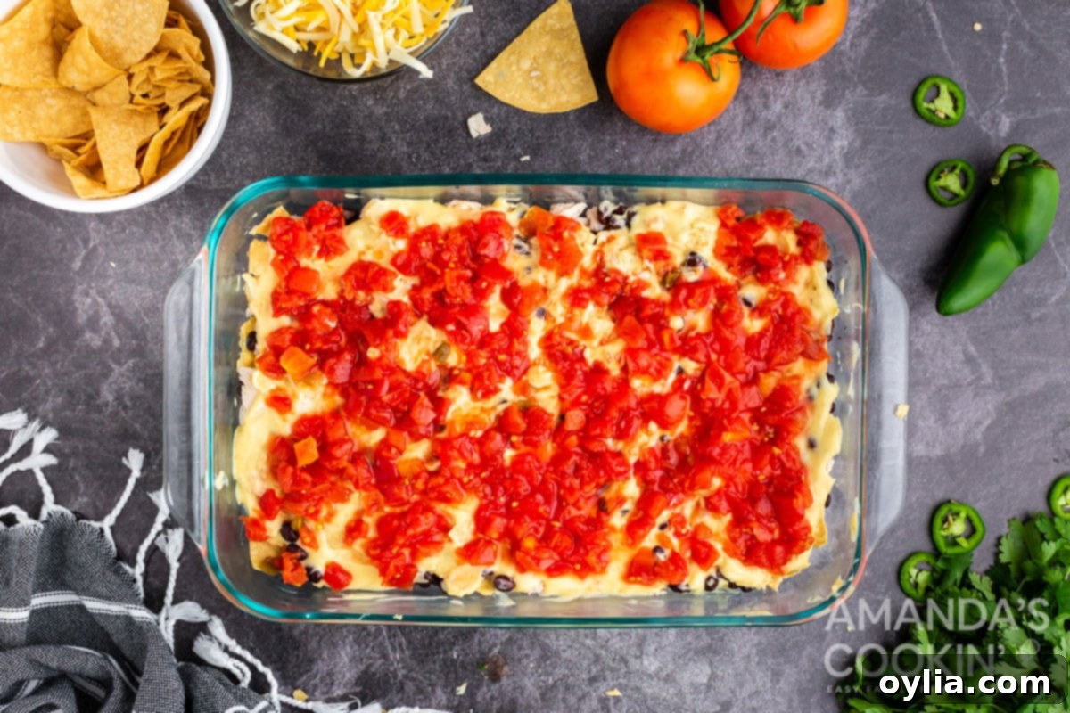 A layer of creamy cumin-infused chicken soup spread over the chicken and beans, topped with canned Rotel tomatoes.