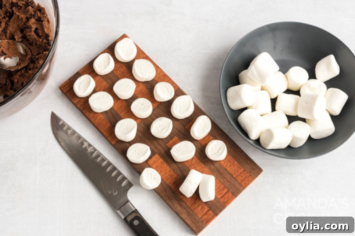 Marshmallows on a cutting board, halved and ready to top cookies