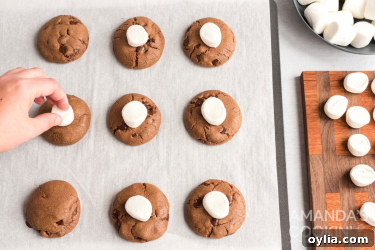 Pressing marshmallows onto hot cookies for the ultimate hot cocoa treat