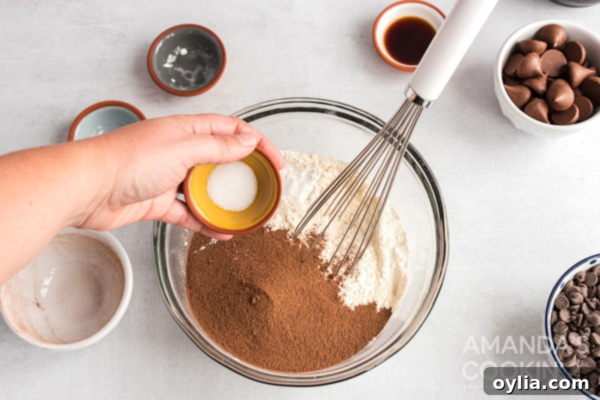 Adding dry ingredients to a bowl, preparing the hot cocoa cookie dough