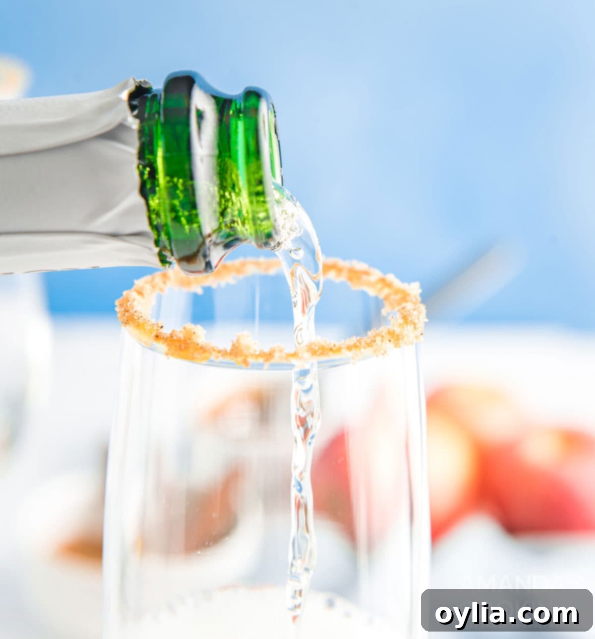 Pouring chilled champagne into a champagne flute with a caramel and cinnamon-sugar rim.