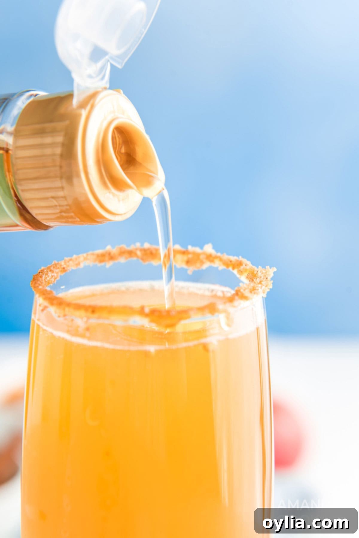 Adding a dash of caramel beverage syrup into a prepared champagne flute with mimosa mixture.