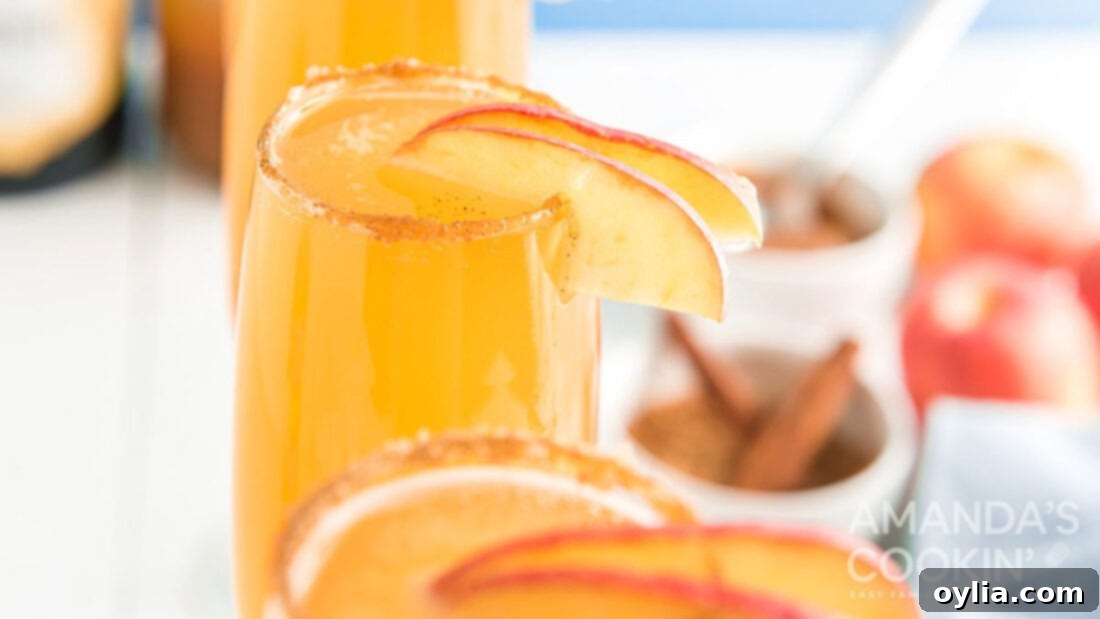 Glasses of caramel apple mimosas, garnished with fresh apple slices, arranged on a tray, ready to serve.
