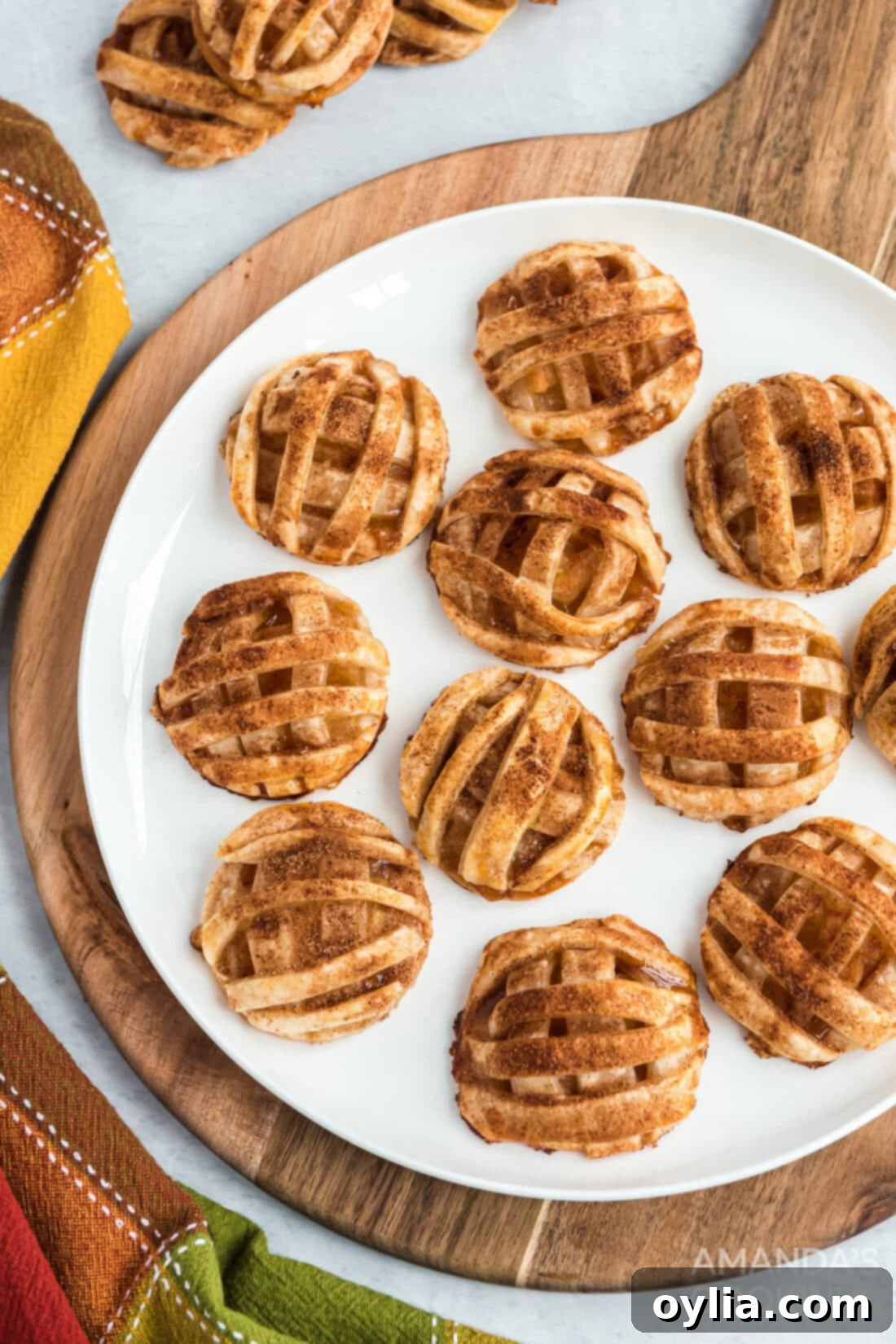 Apple Crumble Cookies 2 Delicious apple pie cookies artfully arranged on a rustic round wooden cutting board, showcasing their golden-brown crust and intricate lattice tops.