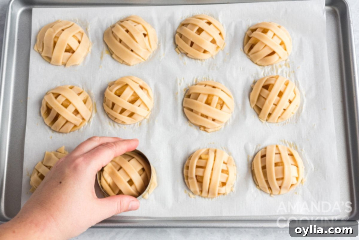 A cookie cutter being used to trim excess dough from the edges of an apple pie cookie, creating a neat round shape.