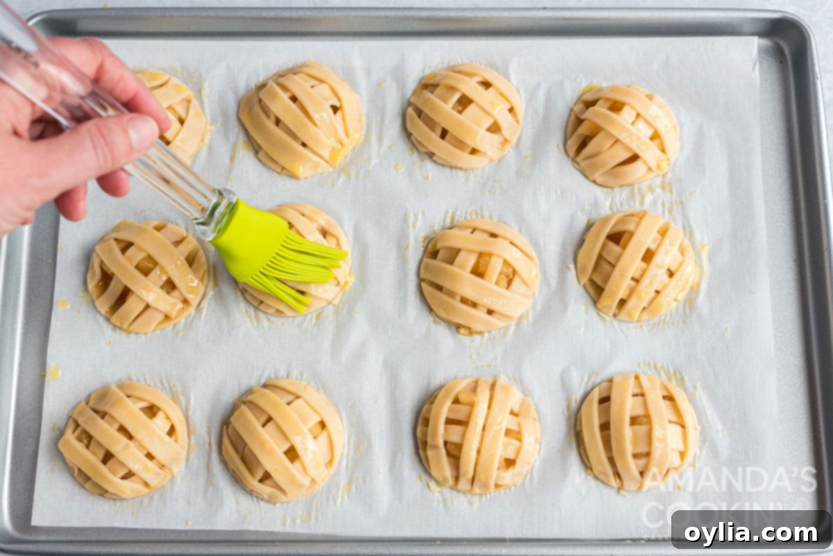 Egg wash being brushed onto the lattice top of an apple pie cookie before baking.