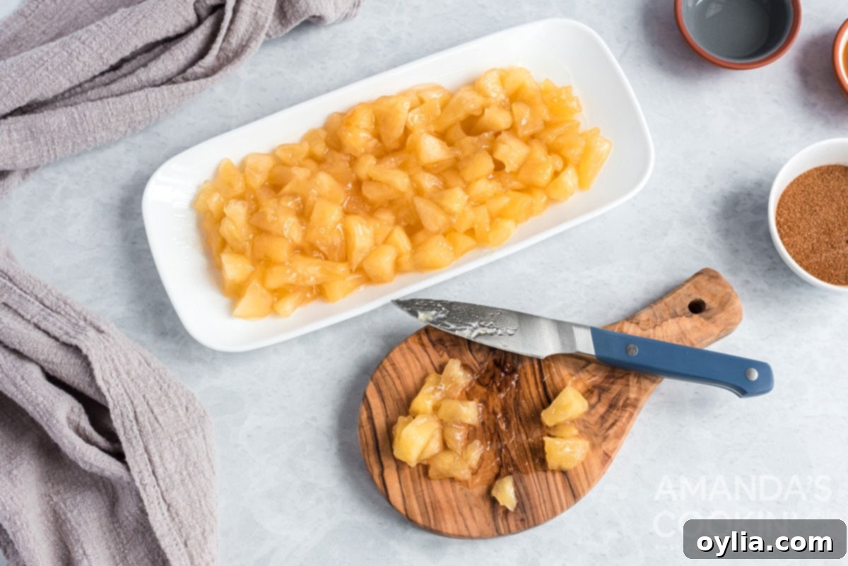 Close-up of canned apple pie filling being drained and apples being diced on a cutting board with a knife.