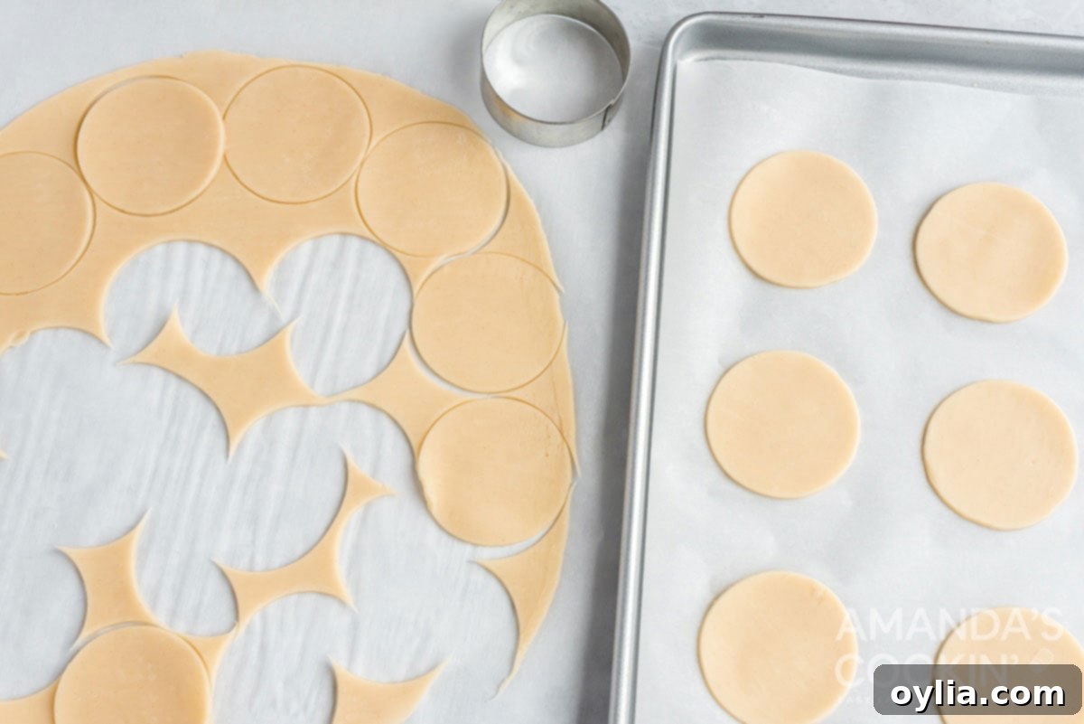 Two rounds of pie dough with several 2.5-inch circles already cut out, ready for filling.
