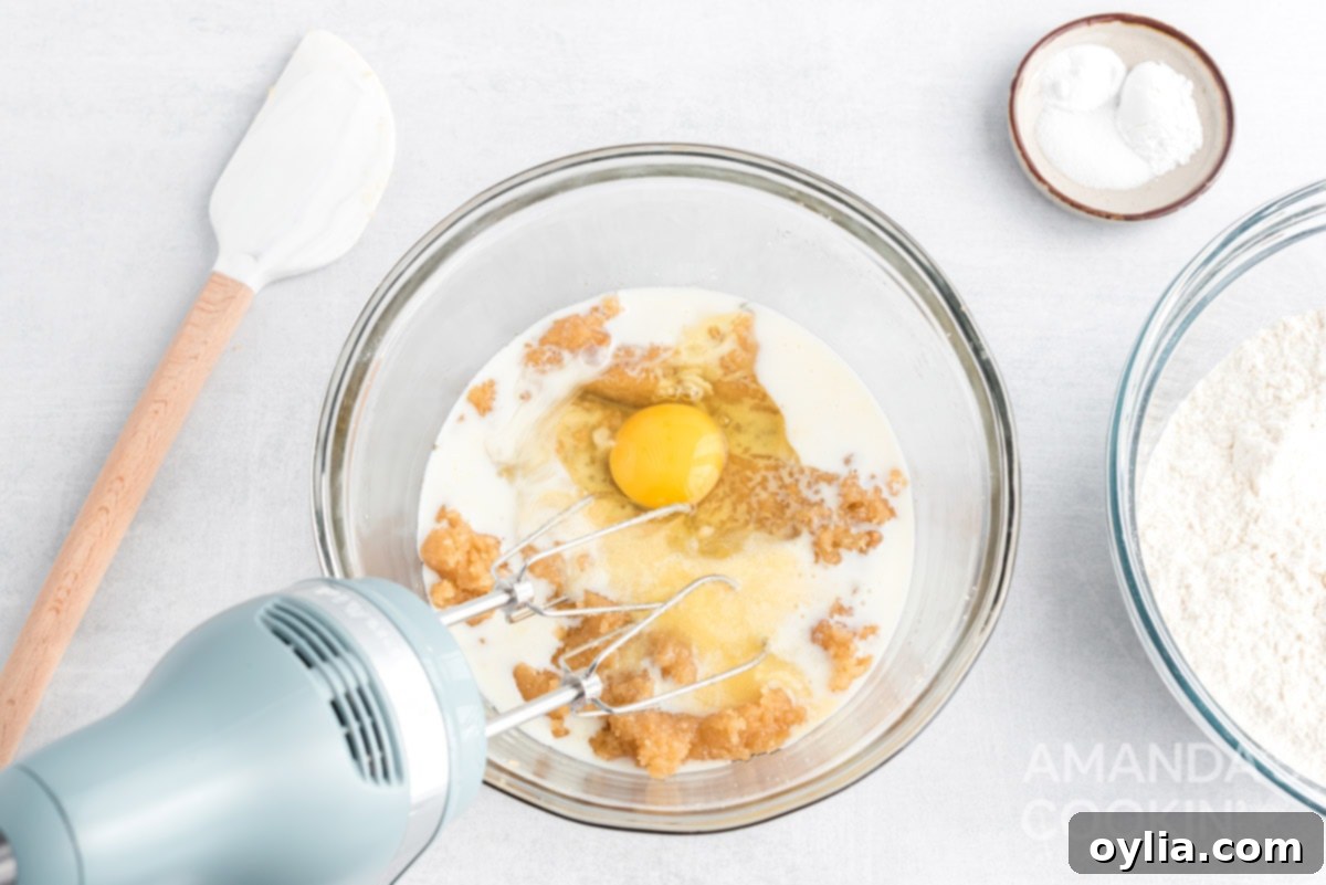 Adding an egg to the wet ingredients in a mixing bowl