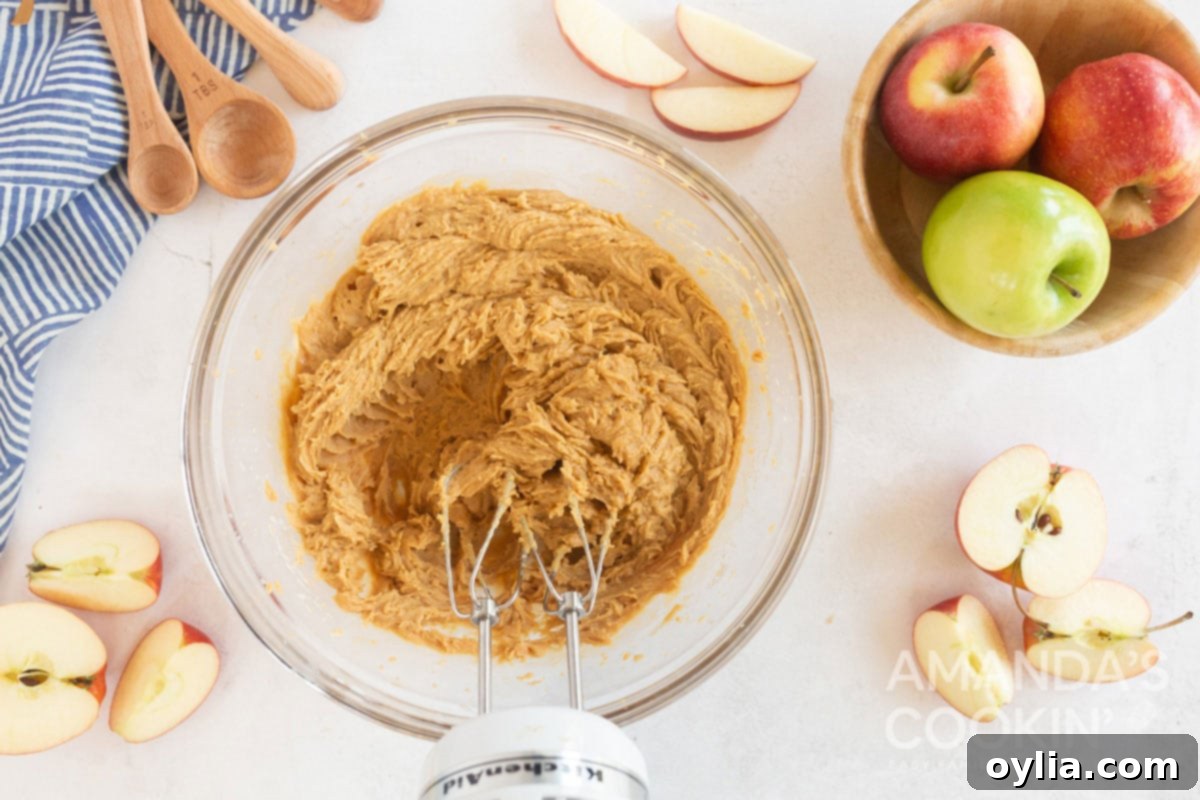 peanut butter apple dip being smoothly blended by a hand mixer in a bowl