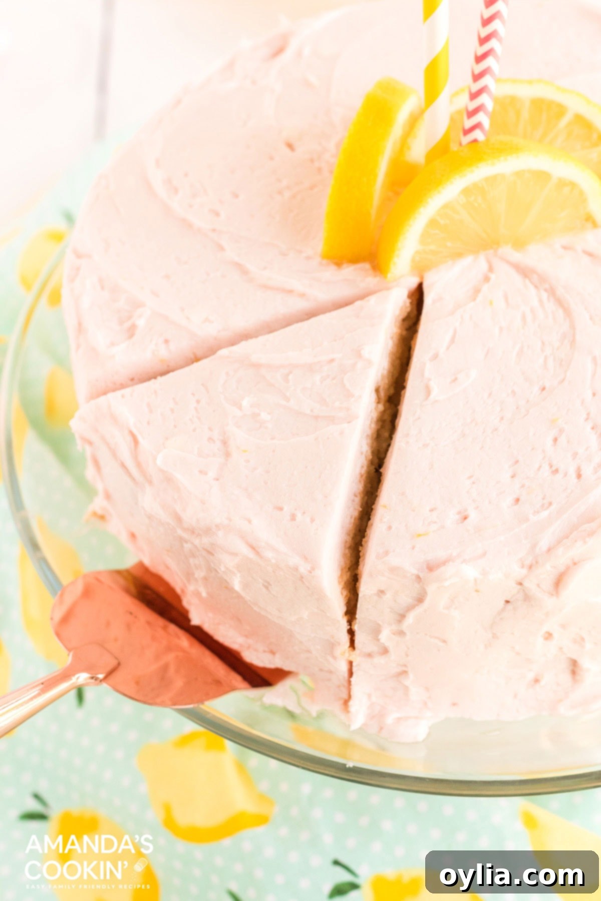 This pink lemonade cake is perfect for summer and will be a huge hit with lemonade fans. Make this beautiful cake from scratch for your next party! slice being removed from a round pink cake with a pie server