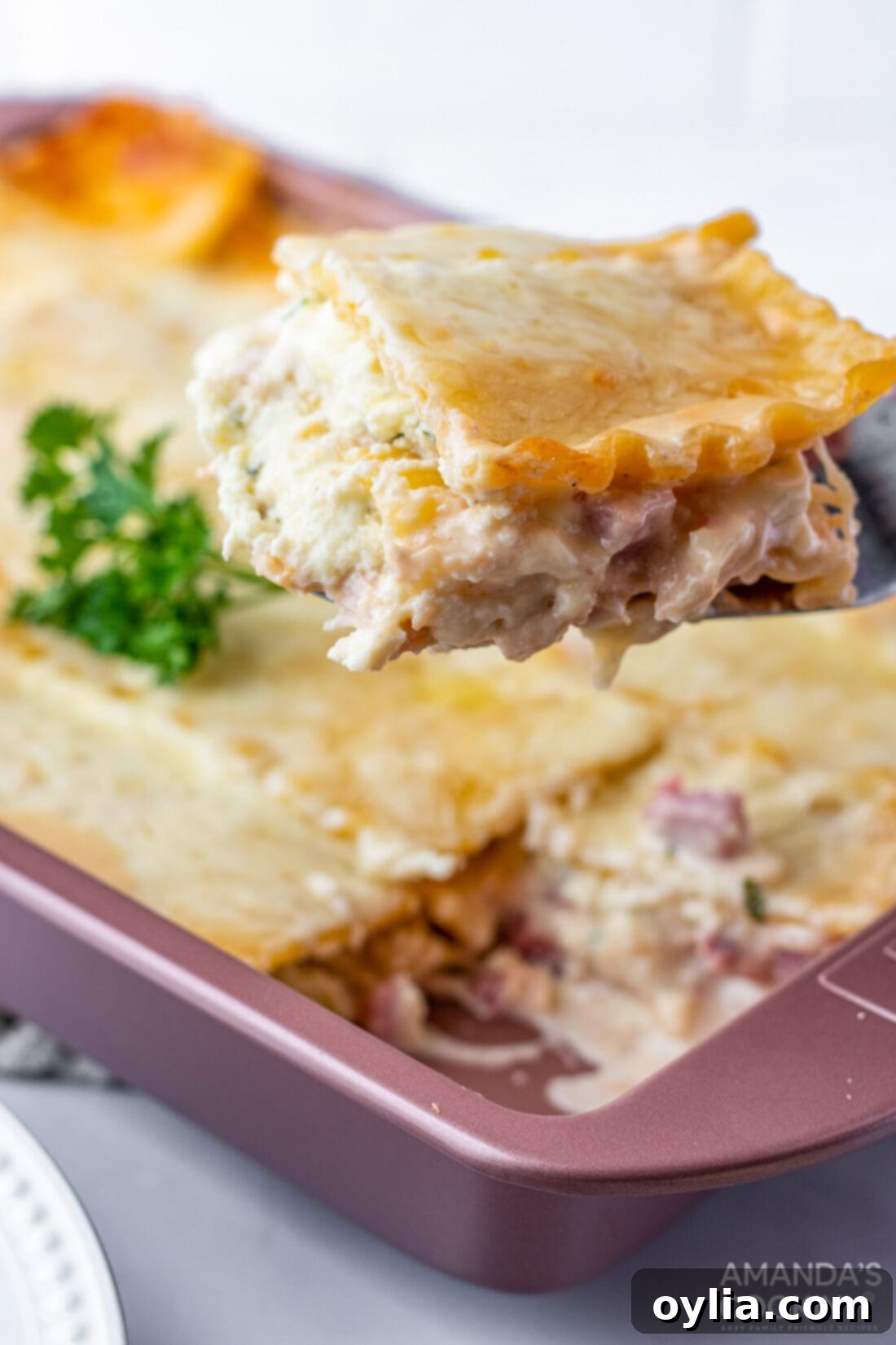Creamy Chicken Cordon Bleu Lasagna 2 A generous slice of creamy Chicken Cordon Bleu Lasagna being lifted from the pan, showing layers of pasta, ham, chicken, and cheese.