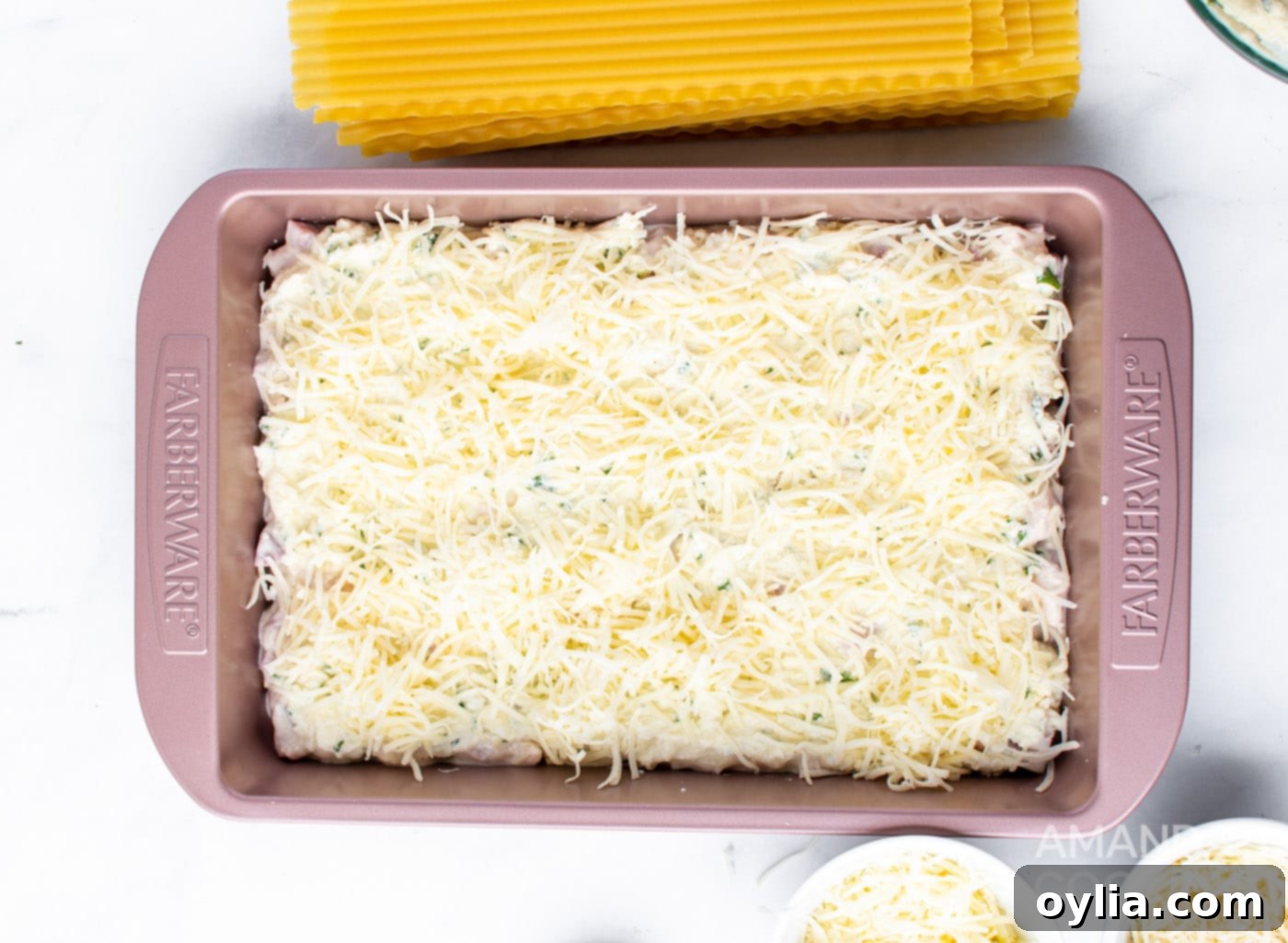 Layering cheese over noodles and ricotta mixture in the baking pan.