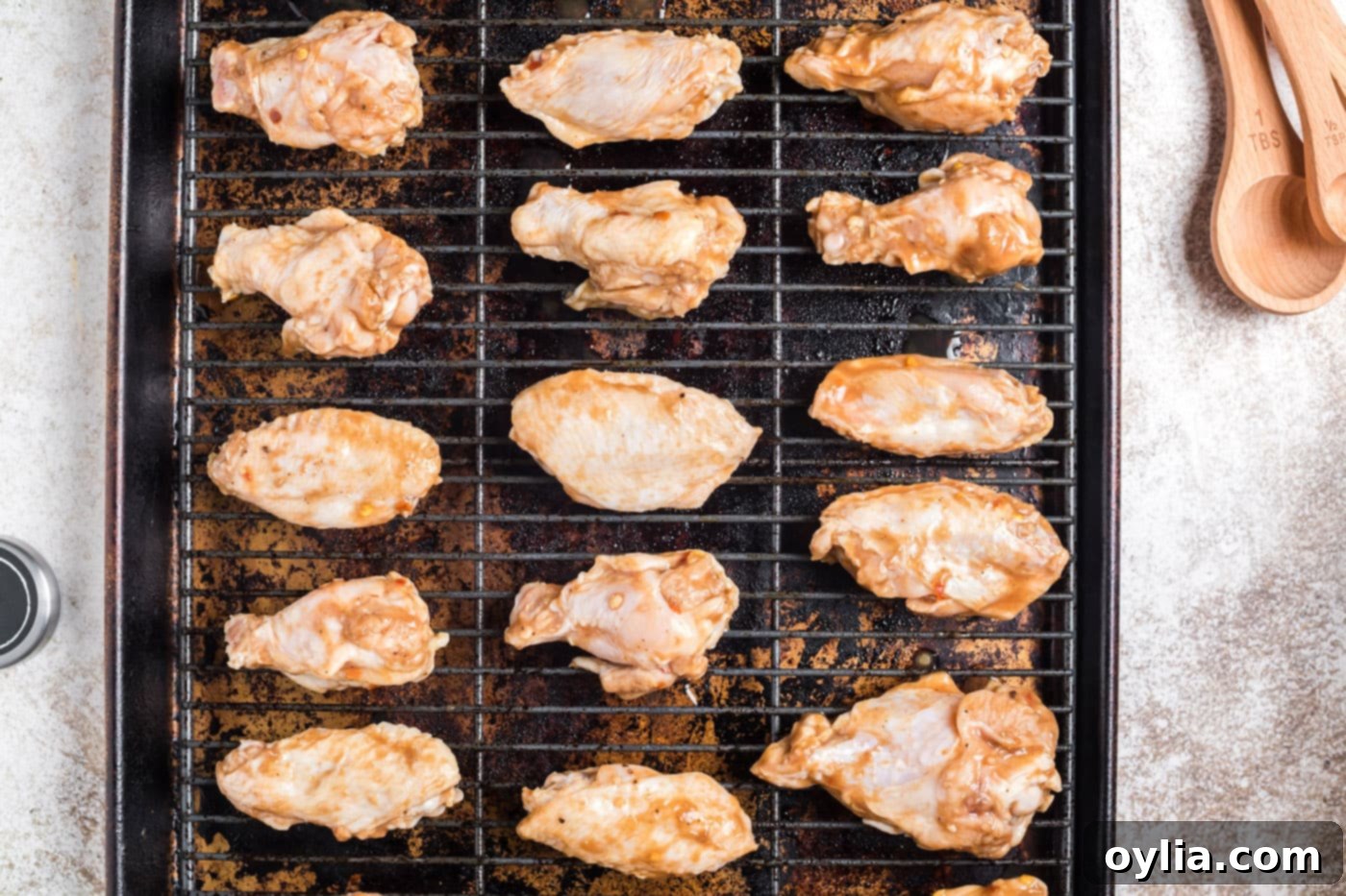 Spicy chicken wings laid out in a single layer on a wire rack over a baking sheet, ready for the oven.