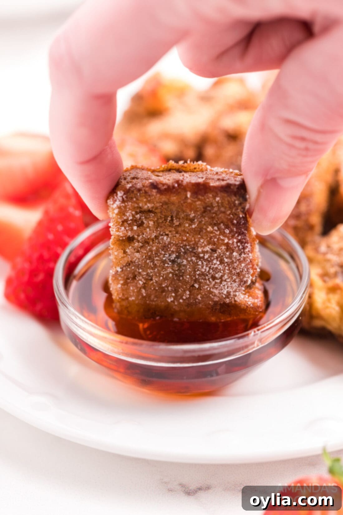 dipping a french toast stick in syrup