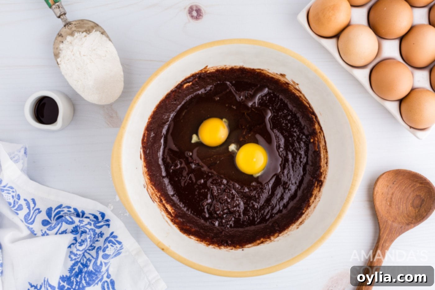 Adding eggs and vanilla extract to the chocolate and sugar mixture