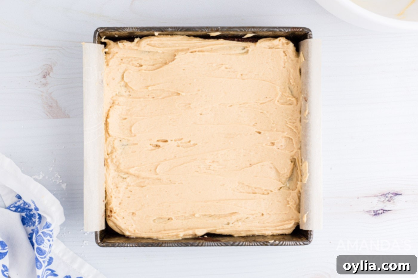 Creamy peanut butter frosting being spread over cooled fudge brownies