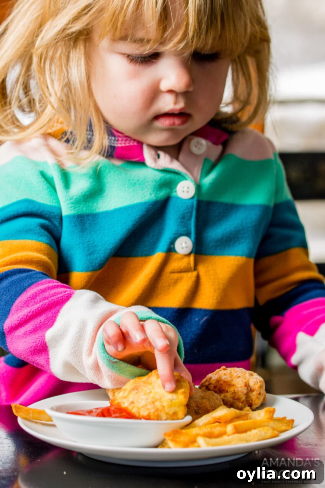 little girl dipping an air fryer chicken nugget